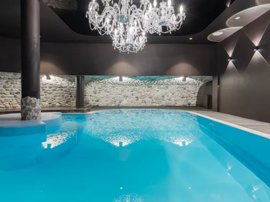 Luxury indoor swimming pool with crystal chandelier and stone wall decor